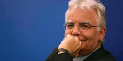 Headshot of Bill Kenwright CBE against a blue background