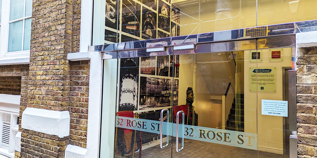 The image shows the front of the Rose St building. The entrance doors are glass and you can see inside the foyer where there is a Laurence Olivier statue and some theatre seats.